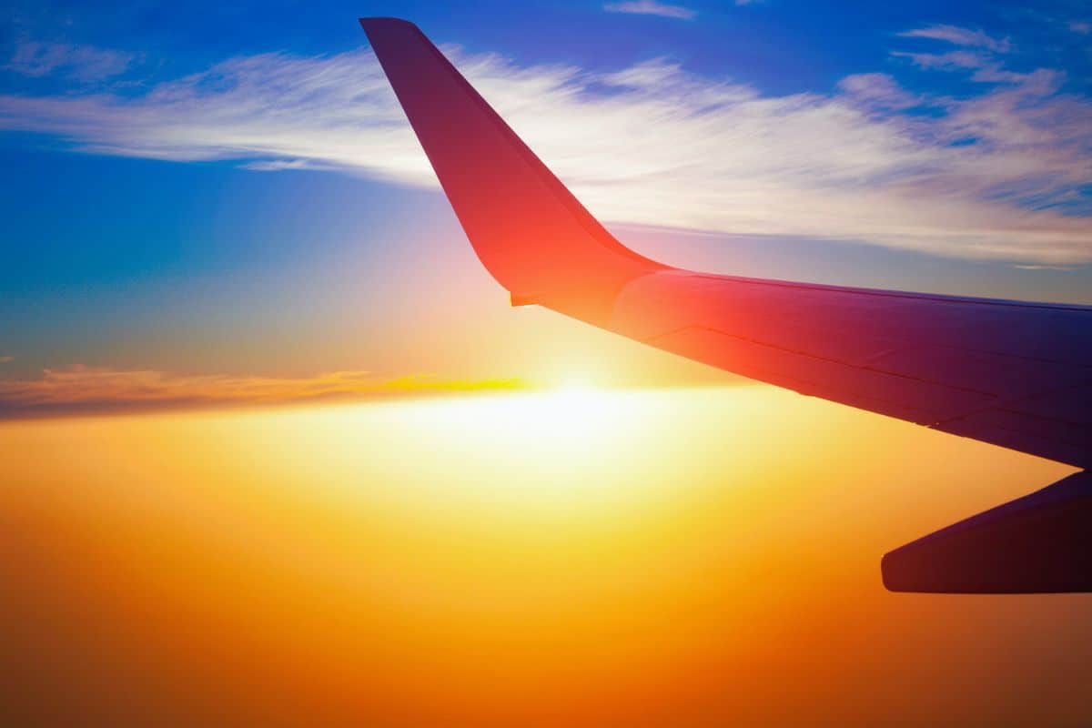 A view of an aeroplane in the sky at sunset.